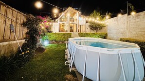 A backyard with a swimming pool, a wooden fence, and string lights. - Casa Viento - Private Pool, Garden & BBQ (San Pedro La Laguna)