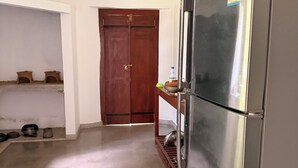 Eine Küche mit einem Edelstahlkühlschrank, einer Holztür und einem Regal mit Küchenutensilien.