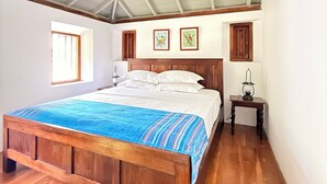 Een slaapkamer met een houten bed, een klein nachtkastje, een raam en een schuin dak.