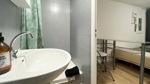 Un baño con lavamanos, cortina de ducha y una estantería de vidrio.