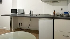 Una cocina compacta con microondas, tostadora y lavabo.