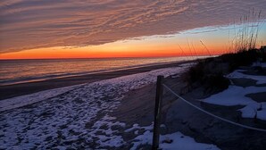 Ein Strand mit Schnee auf dem Boden und einer Seilsperre.