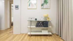 A modern room with a desk, laptop, and a small shelf with rolled towels. - Anne House (Seoul)