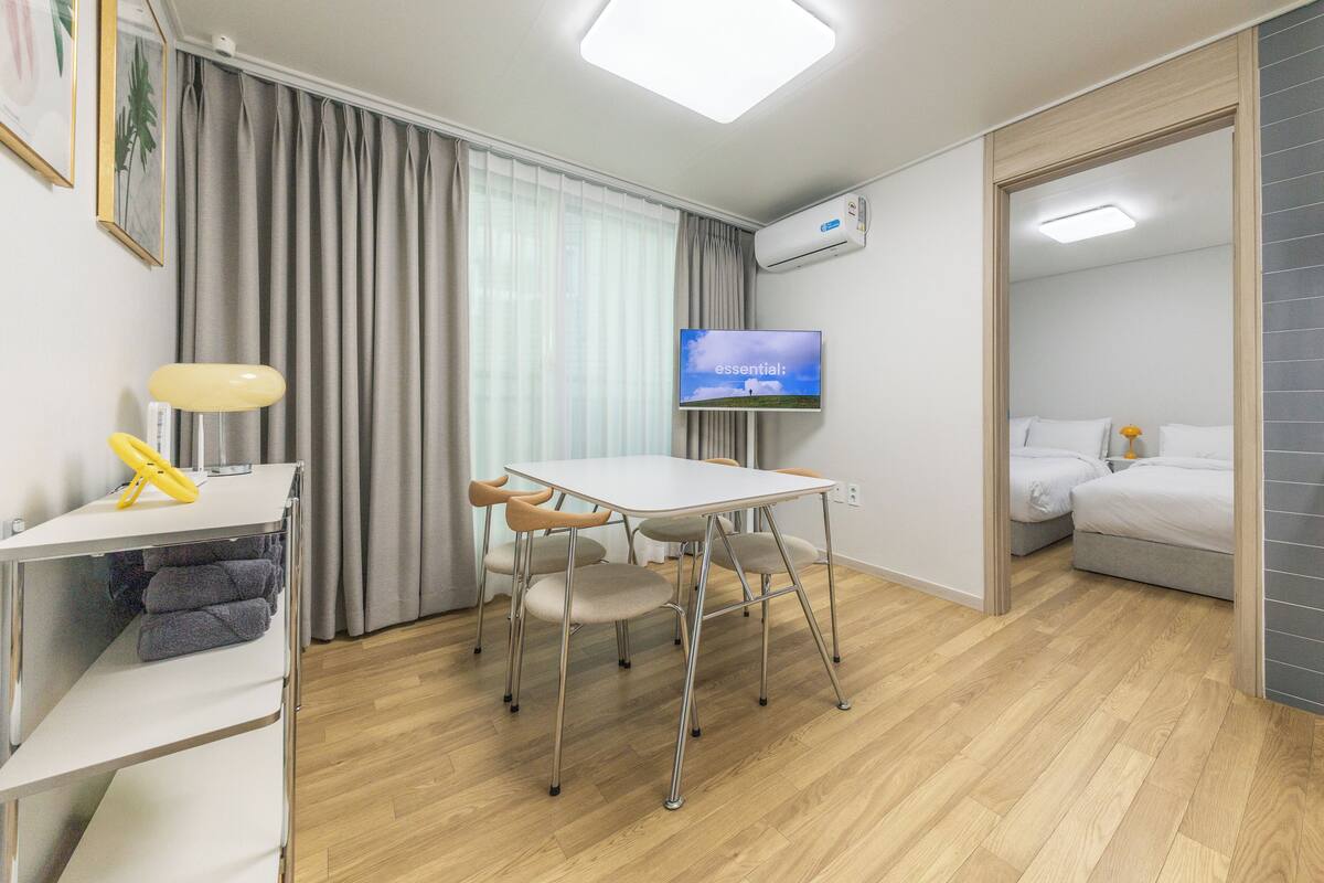 Una habitación de hotel moderna con comedor, televisor de pantalla plana y cama.