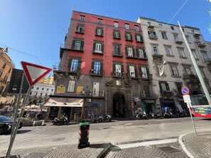 A street corner with a red building, a white building, and a sign for a restaurant. - Dimora dei Marchesi: noble palace in the heart of Naples with 4 elegant suites (Napoli)