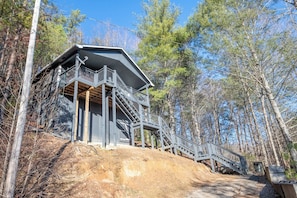 A cabin with a wooden exterior, a balcony, and a staircase leading to a deck.