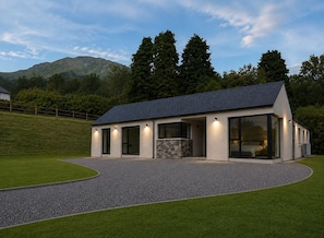A modern house with a stone facade, large windows, and a driveway leading to a grassy area. - Sea Mourne View - Cozy Irish Retreat with Sea Breezes & Mountain Views (Carlingford)