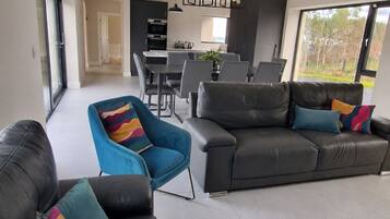 A modern living room with a sofa, chairs, and a dining area with a table and chairs.