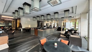 A spacious lobby with a reception desk, seating areas, and modern pendant lighting. - Cozy 1-bedroom apartment with AC and golf course access (Gahunje)