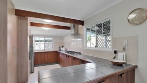 A modern kitchen with wooden cabinets, a large island, and a window with a view. - Fantastic beach house tucked away in paradise (Amity)