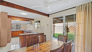A spacious kitchen with a central island, wooden chairs, and a dining table. - Fantastic beach house tucked away in paradise (Amity)
