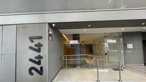 A modern building entrance with a glass door, a metal handrail, and a tiled floor. - Apartment in Nuñez (Buenos Aires)