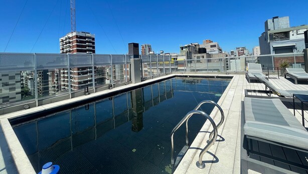 A rooftop pool with a clear view of the cityscape, including high-rise buildings and a construction crane. - Apartment in Nuñez (Buenos Aires)