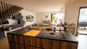 Een moderne keuken met een centraal eiland, houten keukenkastjes en een eethoek met een bank en stoelen.