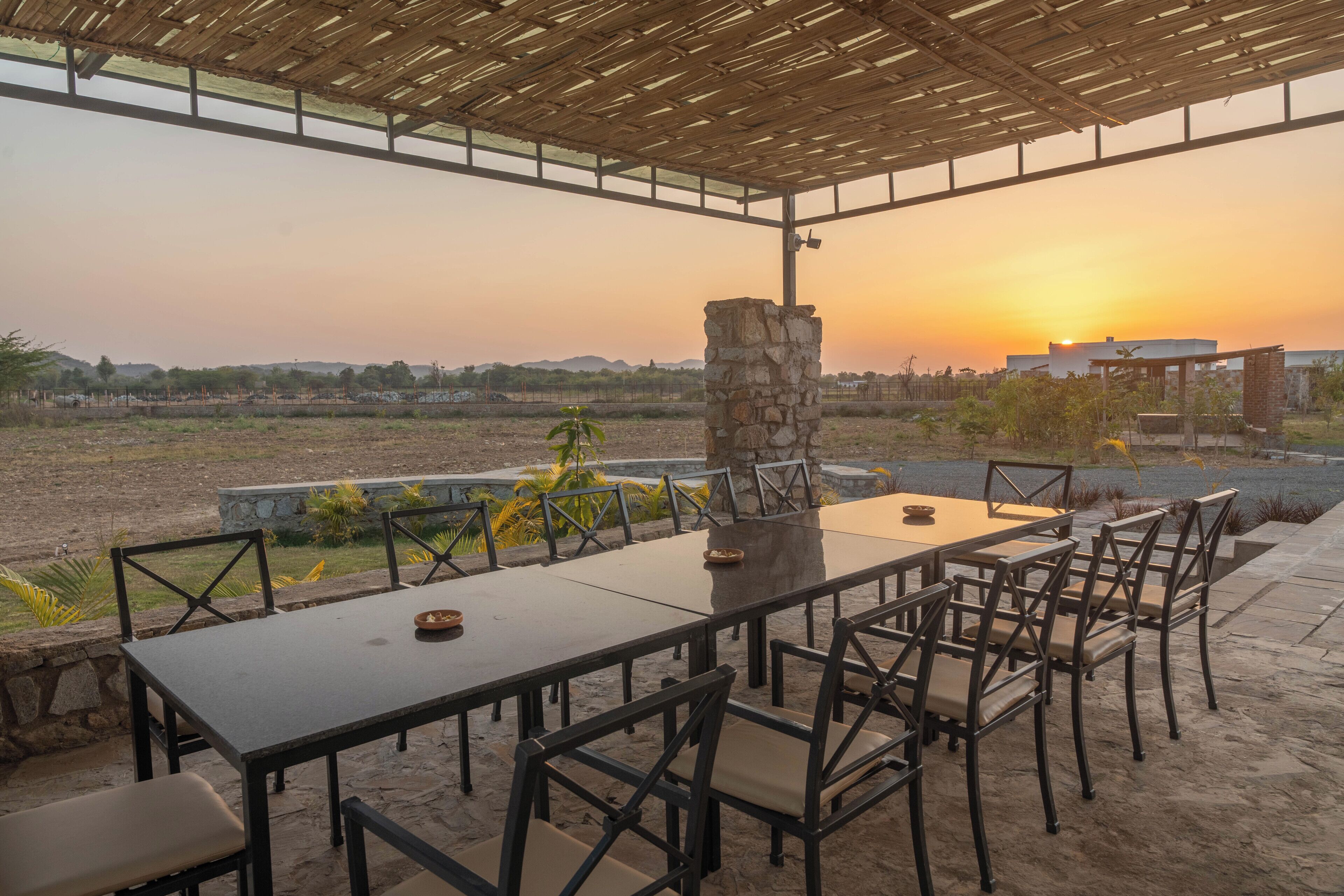 An outdoor dining area with a stone pillar, tables, and chairs.