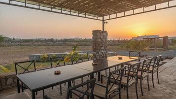 An outdoor dining area with a stone pillar, tables, and chairs.