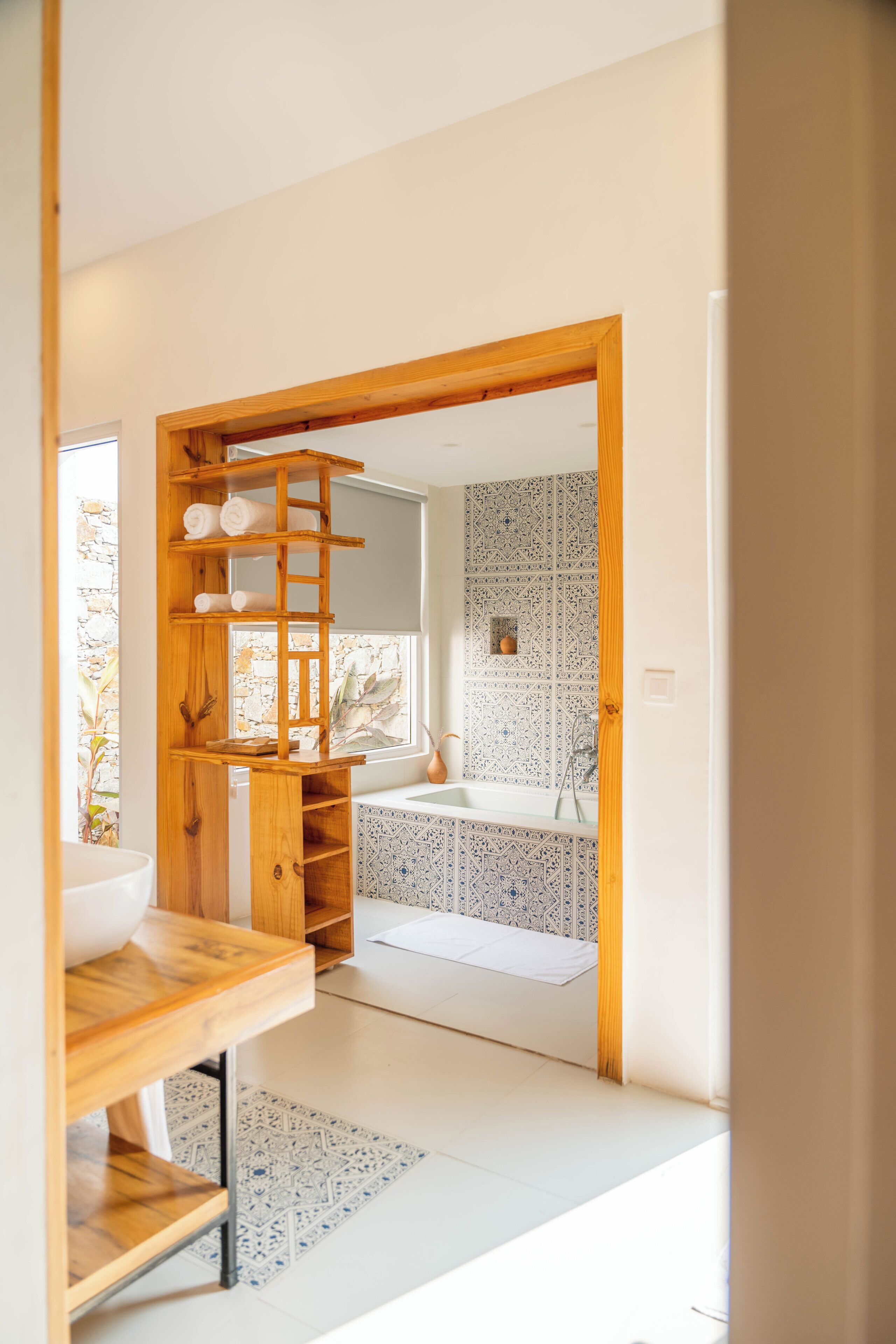 Une salle de bain moderne avec une baignoire, une étagère en bois et des carreaux à motifs.