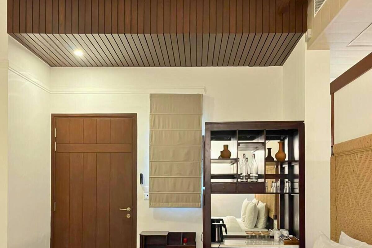 Habitación de hotel con cama, armario de madera, mesita y espejo.