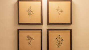 Four framed botanical illustrations on a wall, evenly spaced and illuminated by a ceiling light.