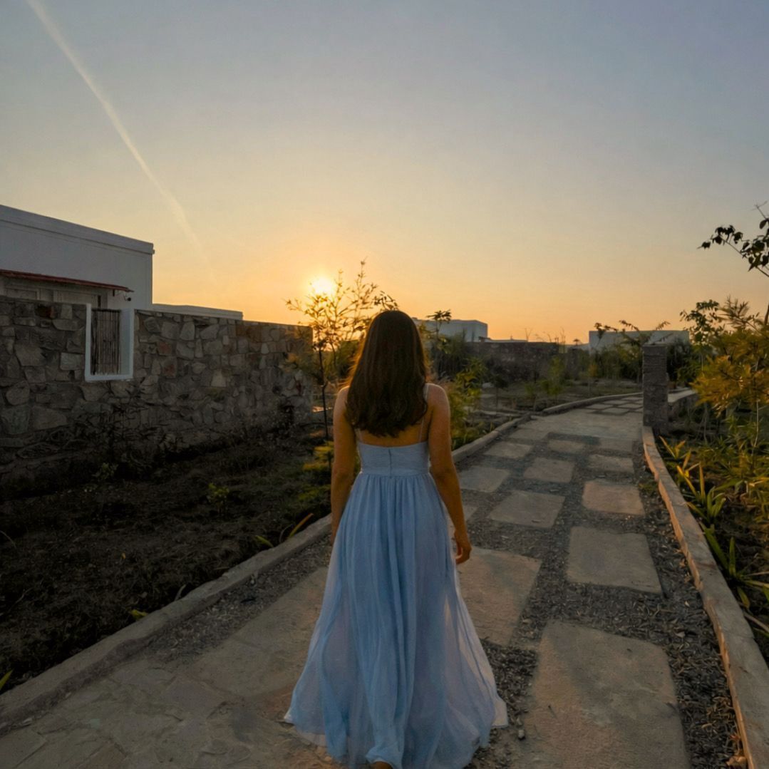 Una mujer camina por un sendero pavimentado con un atardecer al fondo.