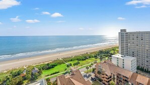 Vistes a la platja amb un hotel i un edifici alt al fons.