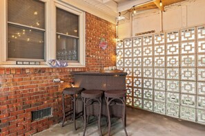 A bar area with a brick wall, a window with blinds, and a decorative wall panel. - Seaside Cabana-Dog Friendly 3BR Cherry Grove (North Myrtle Beach)