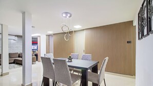 A modern dining area with a rectangular table, grey upholstered chairs, and a hanging light fixture. - 5BR by Lleras Park w Arcade & Foosball (Medellin)