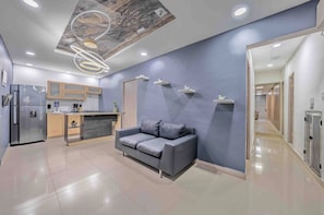 A modern interior with a grey sofa, kitchen area, and a hallway leading to another room. - 5BR by Lleras Park w Arcade & Foosball (Medellin)