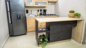 A modern kitchen with a stainless steel refrigerator, wooden cabinets, a black countertop, and a small potted plant. - 5BR by Lleras Park w Arcade & Foosball (Medellin)