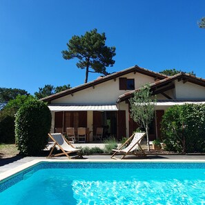 A two-story house with a swimming pool, outdoor seating, and a large tree. - Villa Summer Time by Agence Bru - 683534 (Lacanau)