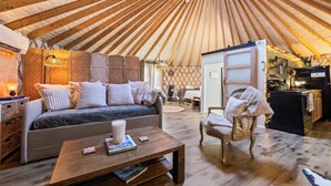 L’intérieur chaleureux d’une yourte, avec un canapé, une table basse en bois et un coin repas.