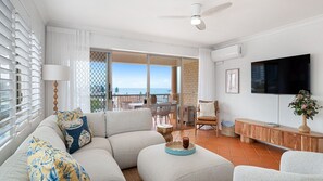 Un soggiorno moderno con un divano, una TV e vista mare.