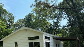 A small white cabin with a porch and a fenced-in area. - Welcome to the Savanna Shire! Cozy one room cabin for a lovers getaway! (Thomson)
