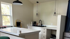 A modern kitchen with a central island, white cabinetry, and pendant lighting. - Welcome to the Savanna Shire! Cozy one room cabin for a lovers getaway! (Thomson)