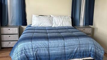 A bedroom with a bed, two nightstands, and a wooden floor.