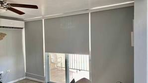 Une pièce dotée d’un ventilateur de plafond, d’une porte-fenêtre coulissante donnant sur un espace extérieur et d’une chaise.