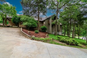 A residential property with a covered porch, a landscaped front yard, and a driveway leading to the entrance. - Eagles Landing (Branson)