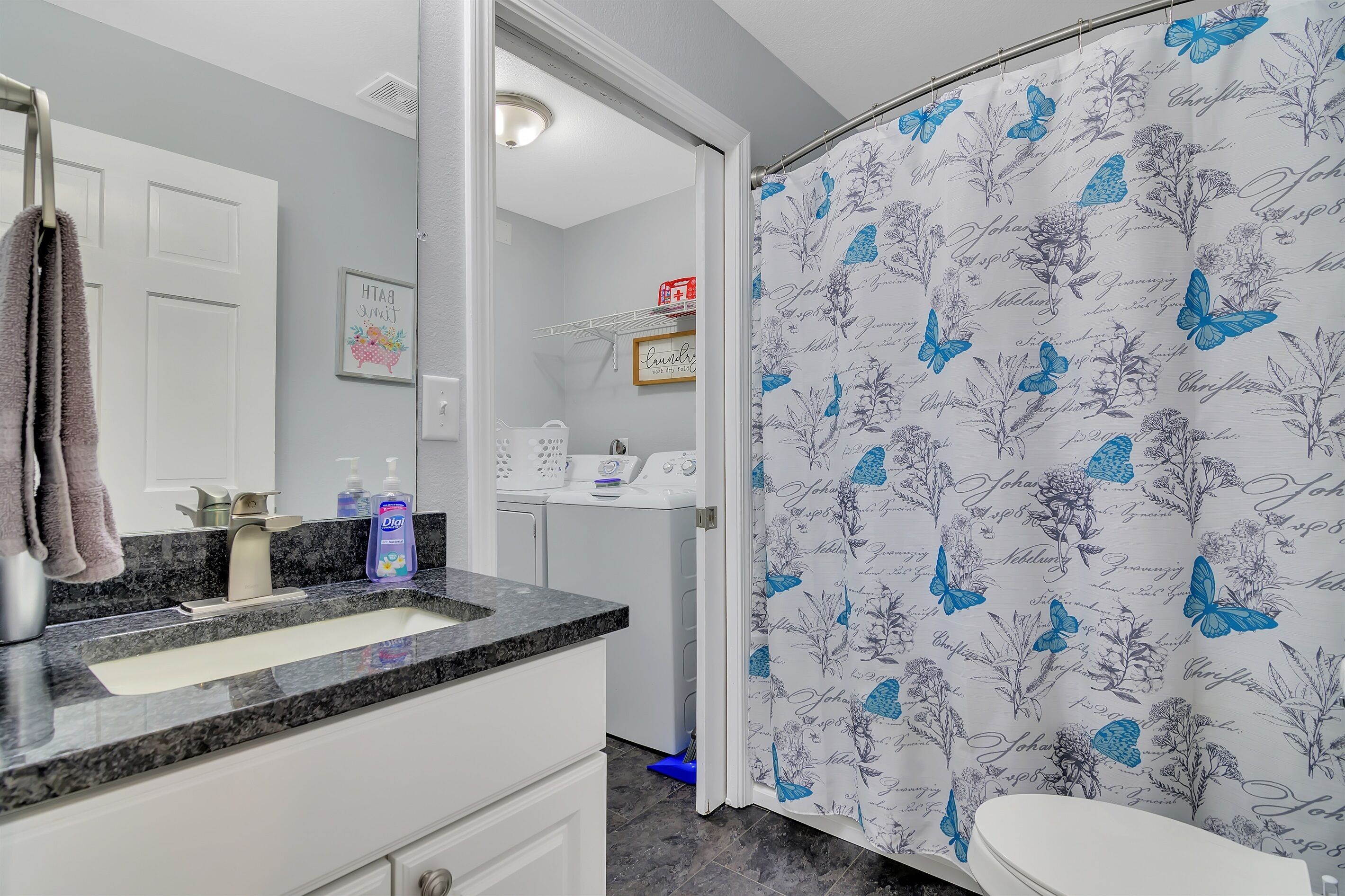 A bathroom with a sink, mirror, and a shower curtain with a butterfly pattern.