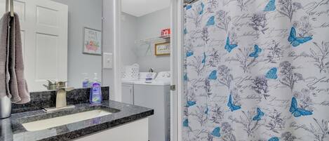 A bathroom with a sink, mirror, and a shower curtain with a butterfly pattern.