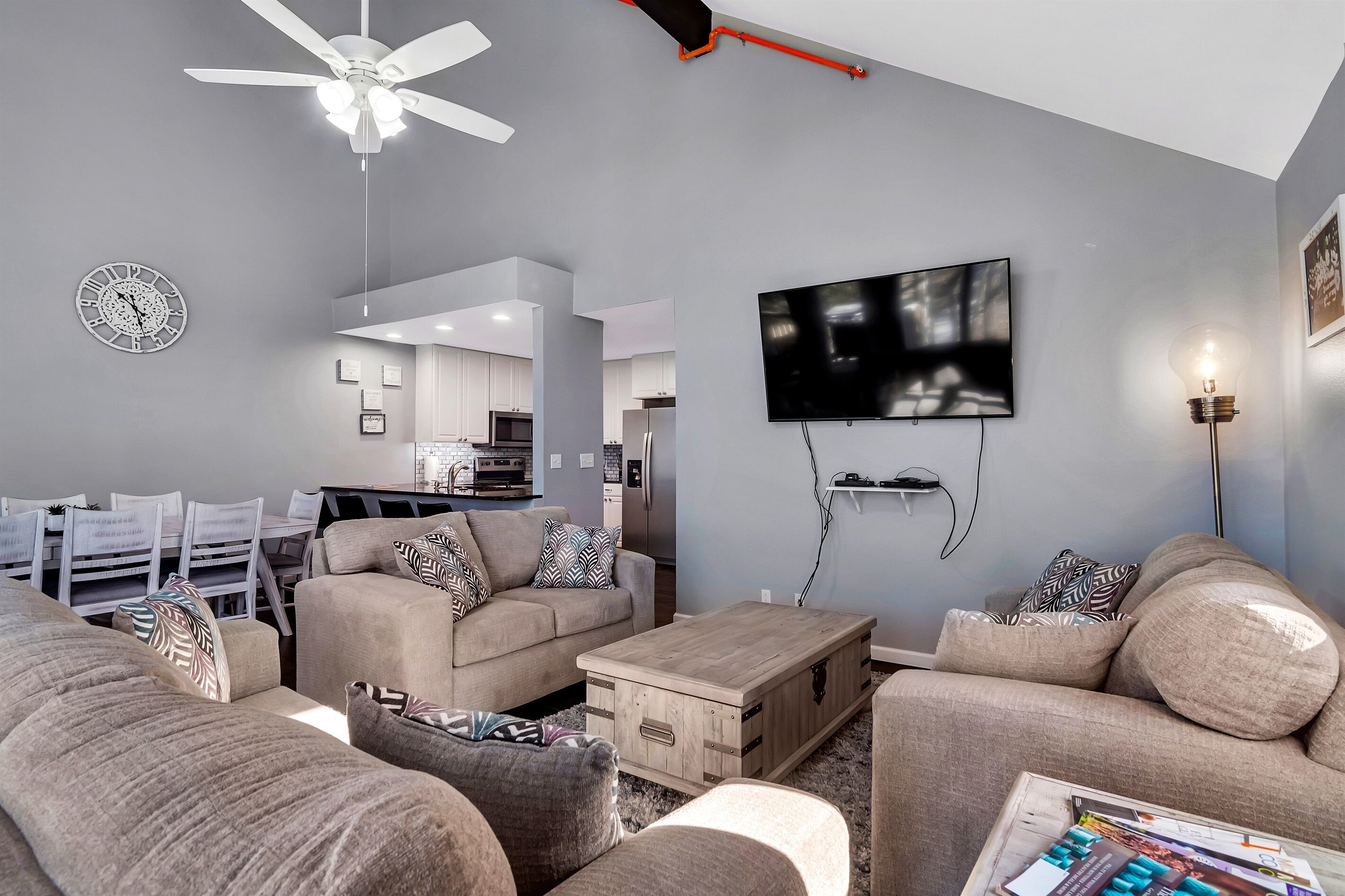 Ein modernes Wohnzimmer mit einer Couch, einem Couchtisch und einem an der Wand montierten Fernseher.