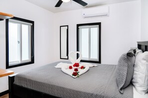 Una camera da letto con un letto, due finestre, un condizionatore d'aria e una ventola a soffitto.