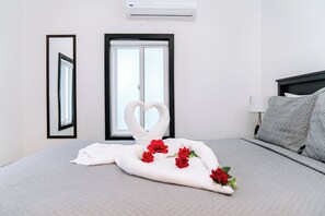 Quarto de hotel com cama, janela, espelho e ar condicionado.
