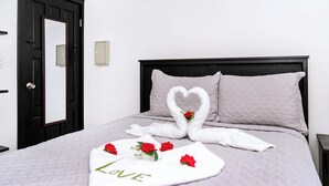 Una cama bien hecha con una disposición de toallas en forma de corazón y una toalla con la palabra 'LOVE' escrita.