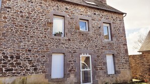 Un edificio de piedra con tres ventanas, una puerta y un pequeño balcón.