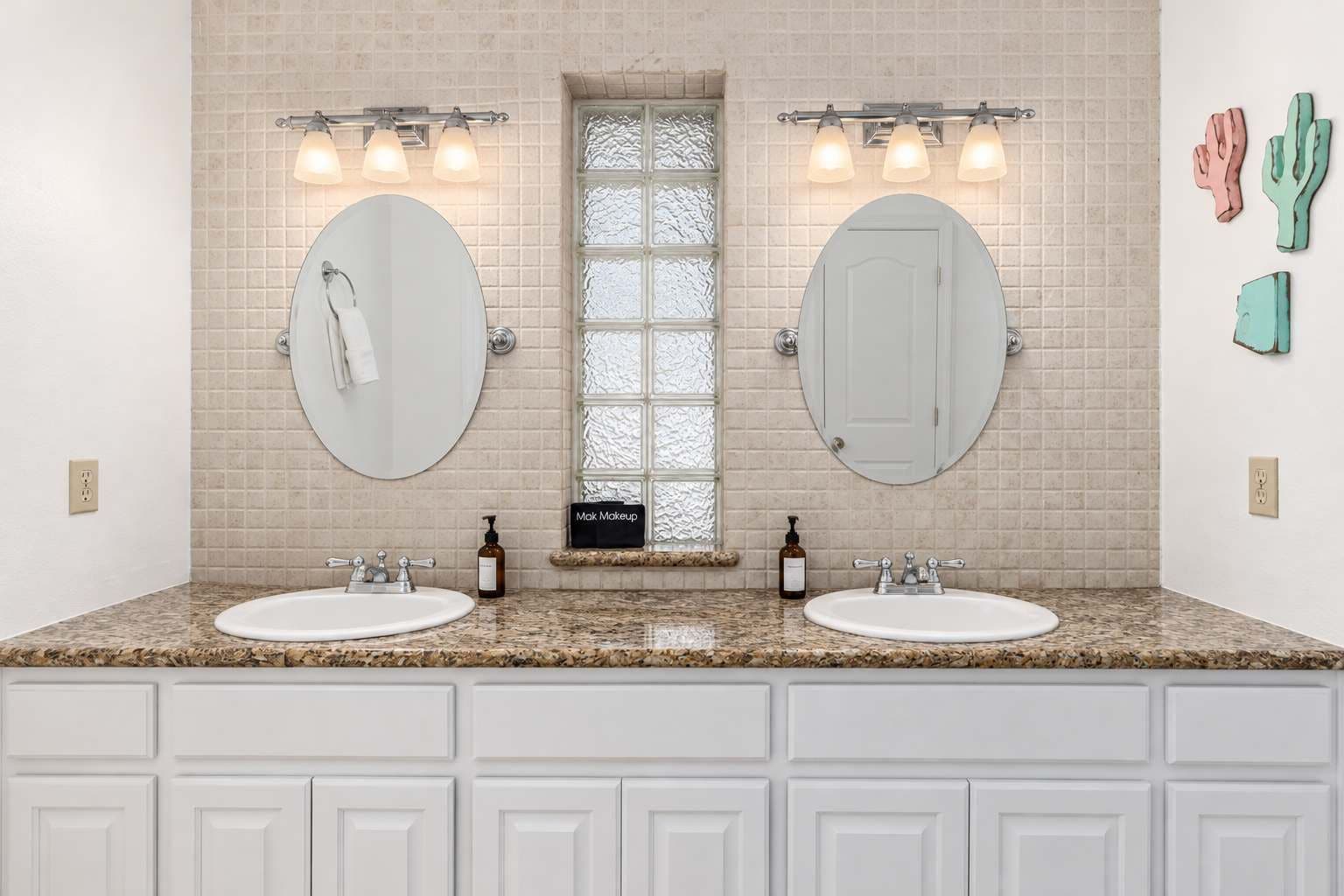 A bathroom with two sinks, a window with frosted glass, and a mirror above each sink.