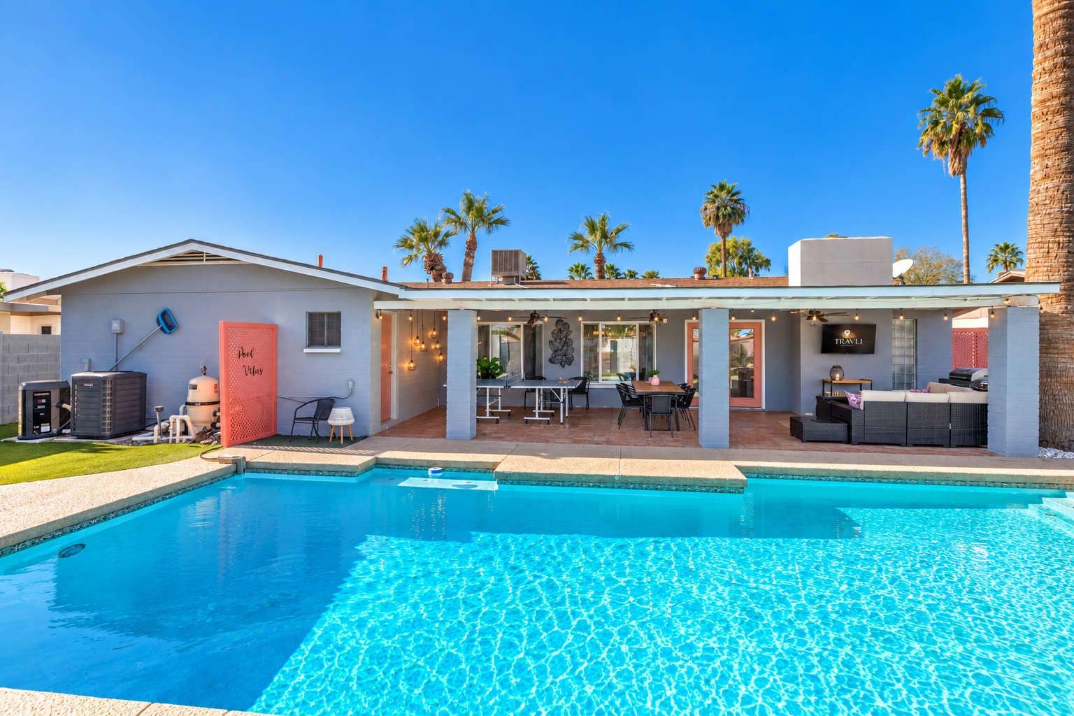 A poolside area with a pool, outdoor furniture, and a building with a red door.