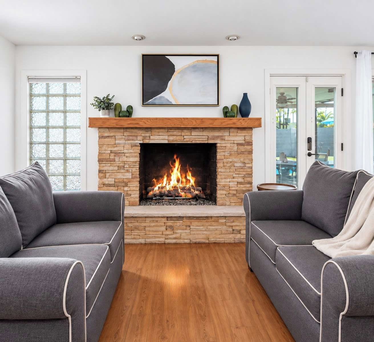 Un salon avec une cheminée, deux canapés gris et un plancher en bois.