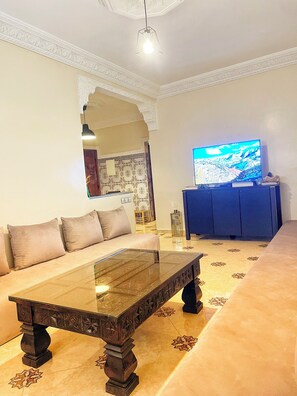 A living room with a sofa, a coffee table, a TV, and a cabinet. - Cosy private room in Atlas Berber House I TAHANAOUT (Tahanaout)