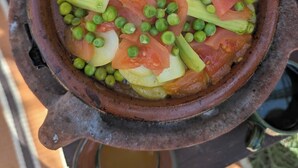 Een terracotta pot gevuld met een stoofpot van groenten en vlees, er stijgt stoom van op.