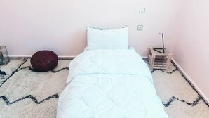Een klein, netjes opgemaakt bed in een kamer met een eenvoudig, schoon design.